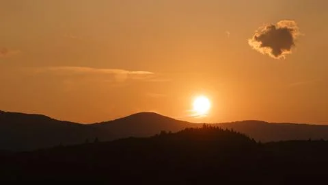 Orange sunset with the setting sun behind the mountains Stock Photos