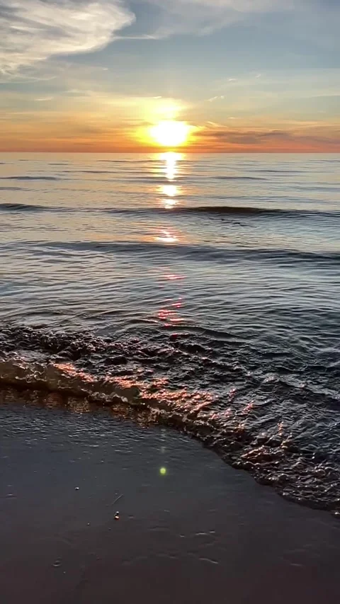 Orange sunset sky with clouds against the backdrop of ocean waves and the coast. Stock Footage 280237981
