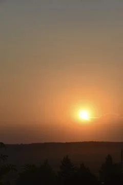 Orange sunset in the summer evening on the background of the forest and the c Stock Photos