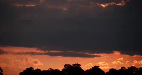 Orange sunset time lapsed as cloud layers flow in multiple directions to horizon Stock Footage 152528565