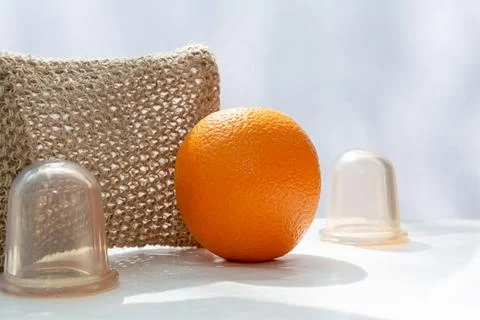 An orange is on the table and next to it are vacuum cans and a mesh washcloth Stock Photos