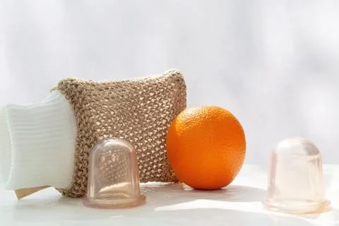 An orange is on the table and next to it are vacuum cans and a mesh washcloth Stock Photos