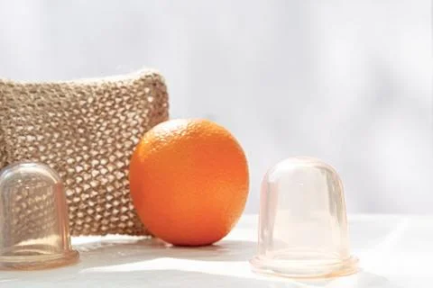 An orange is on the table and next to it are vacuum cans and a mesh washcloth Stock Photos