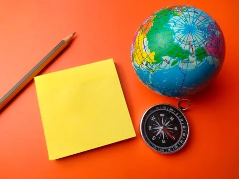 Orange table on a blank sticky note with pencil,compass and earth globe Stock Photos