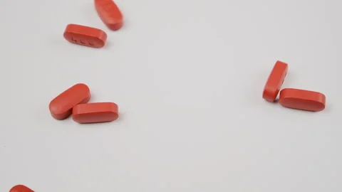 Orange tablets falling out on a white studio table in slow motion Stock Footage 277352490