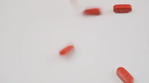 Orange tablets falling out of white plastic tube with an open cap on a white stu Stock Footage 279071673