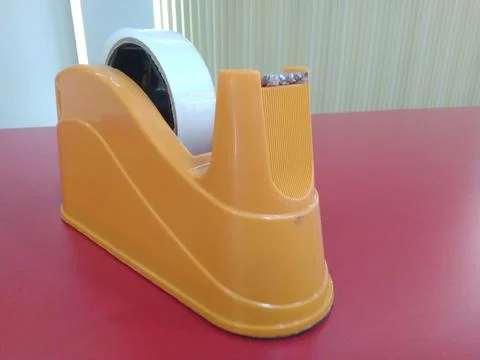 Orange Tape Dispenser on a Red Surface. Stock Photos