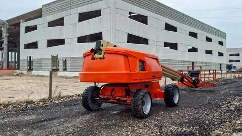 Orange telescopic aerial work platform cherry picker parked outside. Stockfoto's