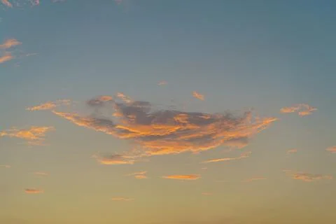 Orange tints clouds in the blue sky at sunset. Stock Photos