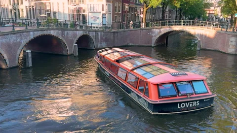 Orange tourist excursion boat floating at the Amsterdam canals Stock Footage 293439232