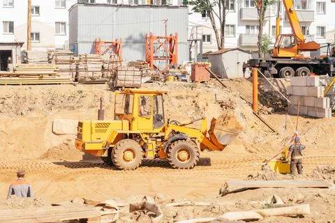 Orange tractor digs pit for construction of multi-storey building in resident Foto stock