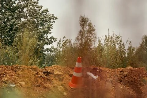 Orange Traffic Cone placed on Soil Mound Near Trees Stock Photos