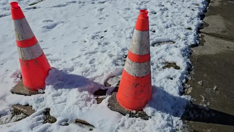Orange traffic cones in snow in winter by concrete sidewalk Vídeo Stock 267053579