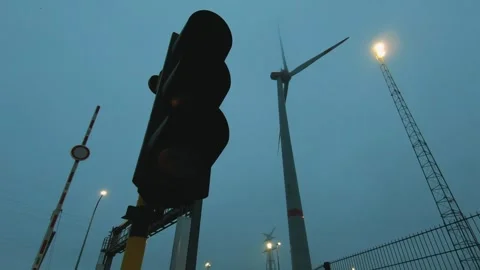 Orange traffic light glowing in thick fog against a backdrop of wind turbines an Video stock 329432530