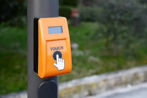 Orange traffic light push button on pillar outdoors Stock Photos