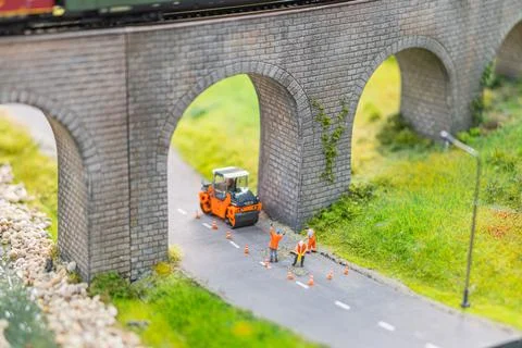 Orange-vested workers construct road at brick archway railway, operating ut.. Stock Photos
