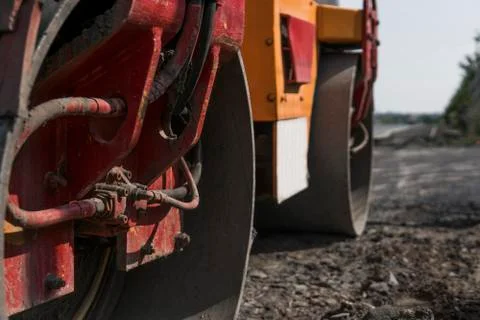 Orange Vibration roller compactor standing on a ground near asphalts road at Stock Photos