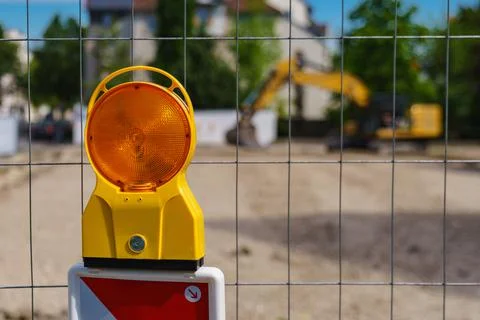 An orange warning light on the grating enclosing a construction site. Selecti Stockfoto's