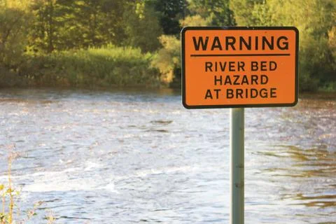 Orange warning river bed hazard at bridge sign Stock Photos