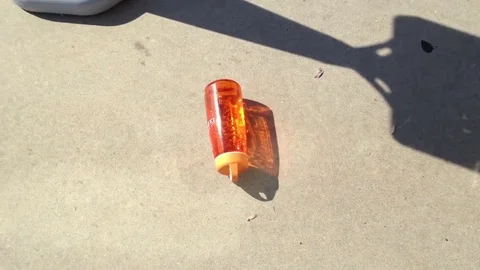 Orange water bottle rolling on sidewalk Stock Footage 74478274