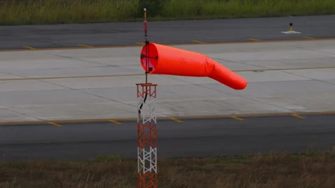 Orange windsock blowing in the wind at airport runway Stock Footage 338304474