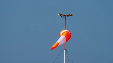 Orange windsock fluttering in wind against clear blue sky background Stock Footage 345363898