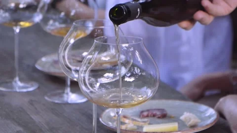 Orange wine poured into a round and ample glass, people in the background Stock Footage 194708352