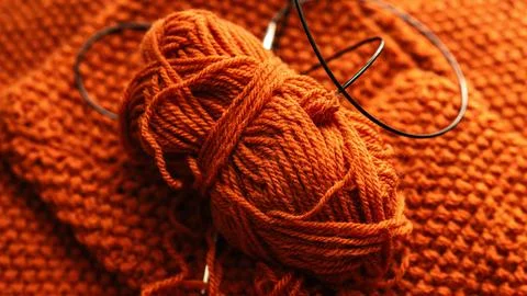 Orange Wool Yarn with Circular Knitting Needle on Knit Fabric Stock Photos