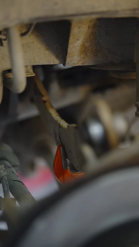 Orange wrench tool gripping a rusty car rear suspension arm Stock Footage 337570534