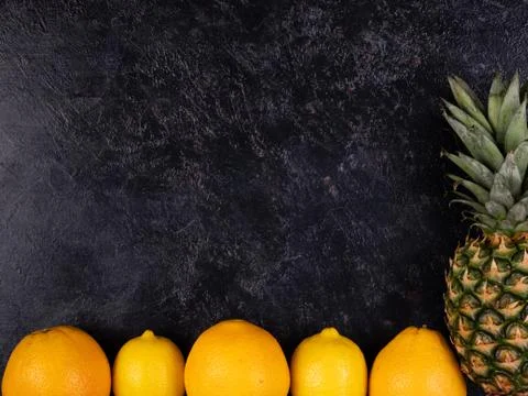 Oranges and pineapple lay on back gray background Stock Photos