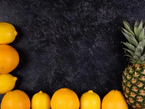 Oranges and pineapple lay on back gray background Stock Photos