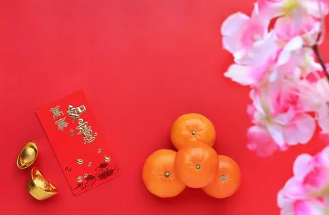 Oranges and red envelope on red background. Chinese text on envelope meaning  Stock Photos