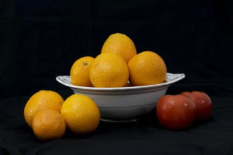Oranges and tomatoes on black background. Stock Photos