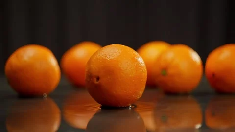 Oranges are spread out on the table and one is spinning in the foreground. Stock Footage 266808632