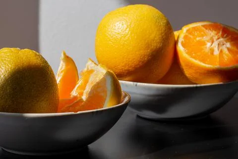 Oranges for breakfast. Healthy fruit in different plates on a black backgroun Stock Photos
