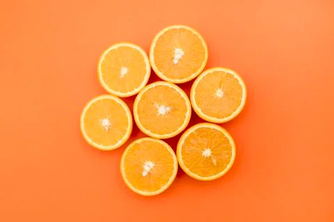 Oranges cut in half on an orange background Stock Photos