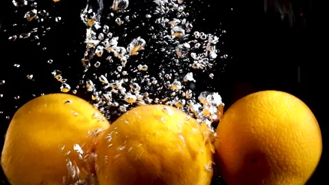 Oranges fall into the water on a black background slow motion Stock Footage 176389613