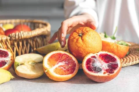 Oranges in female hands on the kitchen table, close-up. Stock Photos