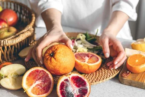 Oranges in female hands on the kitchen table, close-up. Stock Photos