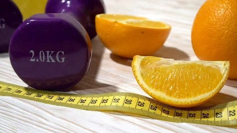 Oranges, juice, dumbbells and measuring tape on wooden background. Stock Footage 70207828