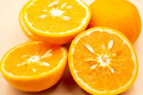 Oranges on pink background. One orange is cut in half, the other is whole. Stock Photos