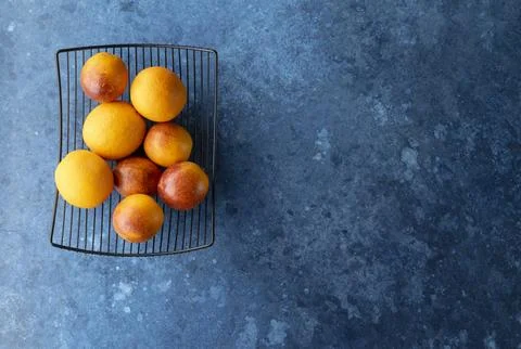 Oranges placed on a wire rack over a textured blue surface Stock Photos