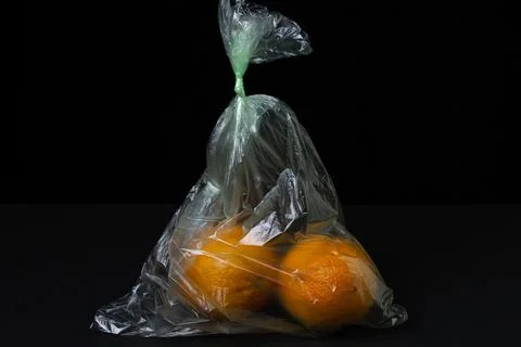 Oranges in a plastic bag on a black background. Oranges on a dark background. Stock Photos