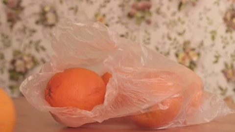 Oranges in a plastic bag fall on a wooden table Stock Footage 150386101