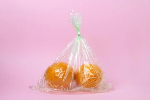 Oranges in a plastic bag on a pink background. Oranges on a light background Stock Photos