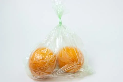Oranges in a plastic bag on a white background. Oranges on a light background. Stock Photos
