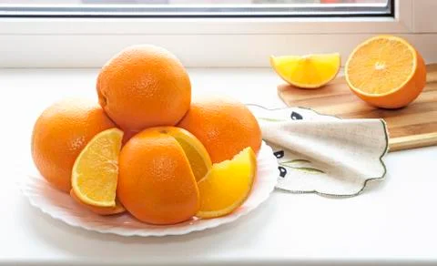 Oranges on a plate on the sill of the window. Stock Photos