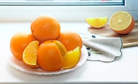 Oranges on a plate on the sill of the window. Stock Photos
