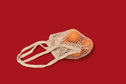Oranges in a string bag on ruby red background Stock Photos