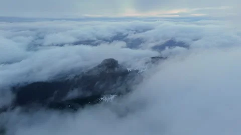 Orbit Aerial drone view above misty cloudscape over mountain peaks at dawn with Stock-Footage 323973201